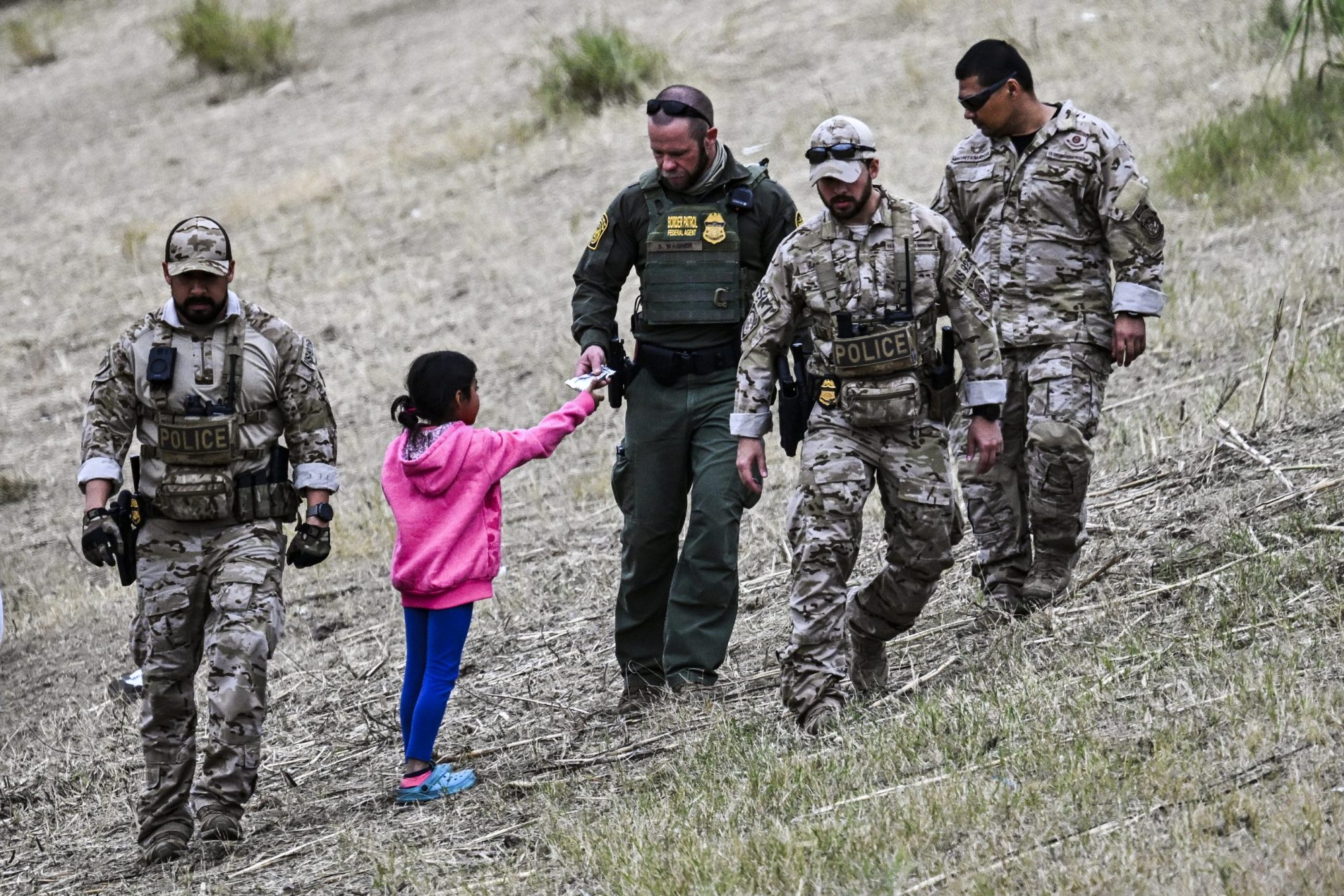 A US Customs and Border Protection officer gives food to an immigrant child waiting to be processed at a US Border Patrol transit center after crossing the border from Mexico at Eagle Pass, Texas on December 22, 2023. Photo by CHANDAN KHANNA/AFP via Getty Images