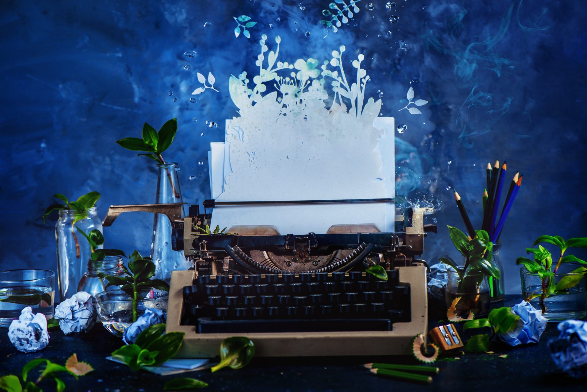 Creative writer workplace with a typewriter and growing plants. Imagination garden concept. Dark still life with action and copy space. Photo via Getty Images